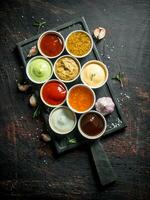 diferente tipos de salsas en bochas en un corte tablero con ajo. foto