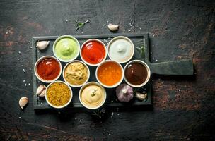 Different types of sauces in bowls on a cutting Board with garlic. photo