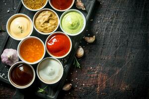 Different types of sauces in bowls on a cutting Board with garlic. photo