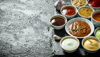 An assortment of different sauces in bowls on a stone Board. photo