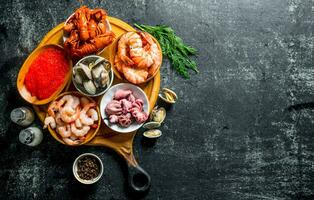 Various seafood on a round cutting Board with herbs and spices. photo