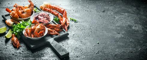 Various seafood on a cutting Board with garlic, lime and parsley. photo