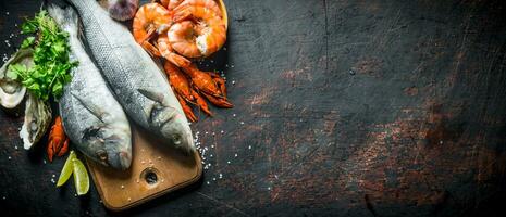 Fresco pescado en un corte tablero con ostras, camarón y cangrejo de río. foto