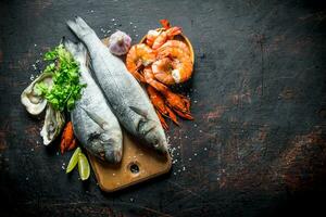 Fresco pescado en un corte tablero con ostras, camarón y cangrejo de río. foto