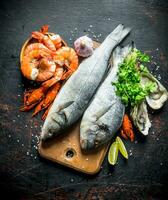 Fresco pescado en un corte tablero con ostras, camarón y cangrejo de río. foto