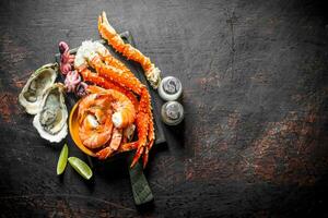 Seafood. Crab, shrimp, oysters, baby octopus on a cutting Board with spices and lime slices. photo