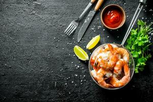 Delicious shrimps in a colander with lime slices, sauce and parsley. photo