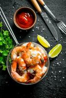 Delicious shrimps in a colander with lime slices, sauce and parsley. photo