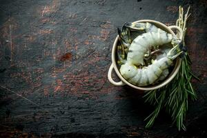 Fresh selected raw shrimps in bowl with rosemary. photo