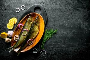 Smoked fish with dill, slices of lemon and onion. photo