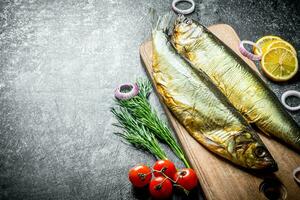 ahumado pescado en un de madera corte tablero con Tomates, eneldo y limón rebanadas foto