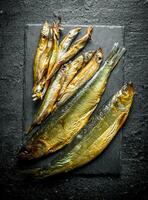 Different smoked fish on a stone Board. photo