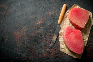 Steaks of fresh raw tuna on paper with a knife. photo