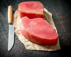 Fillet of raw tuna on the paper with a knife. photo