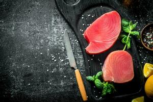 crudo atún filete en un corte tablero con menta, limón y especias foto