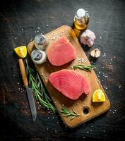 Raw tuna steak with spices, garlic and lemon slices. photo