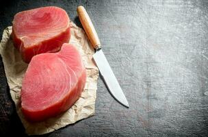 Fillet of raw tuna on the paper with a knife. photo