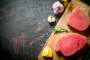 Fresh raw tuna on a cutting Board with lemon and garlic. photo