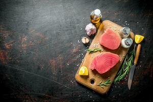 Raw tuna steak with spices, garlic and lemon slices. photo