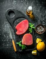 Raw tuna fillet on a cutting Board with mint, lemon and spices. photo