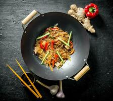 Delicious cellophane noodles in a frying pan wok with chopsticks. photo