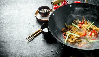 Hot cellophane noodles in a frying pan wok with bell peppers, cucumber and carrots. photo