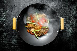 Hot cellophane noodles in a frying pan wok with bell peppers, cucumber and carrots. photo