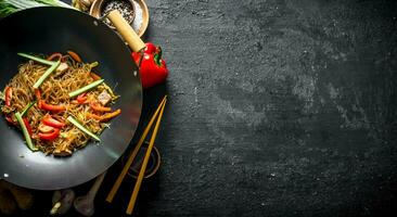 cocido chino tallarines celofán wok con soja salsa en un cuenco y con palillos. foto