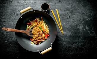 Chinese cellophane pasta in a frying pan wok with spatula and chopsticks. photo