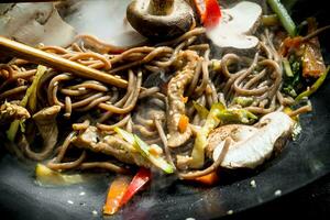 caliente soba tallarines en un wok pan con hongos, salsa y carne de res. foto