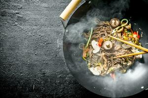 Hot soba noodles in a wok pan with mushrooms, sauce and beef. photo