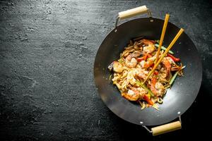 Chinese Udon noodles in a wok pan with chopsticks. photo