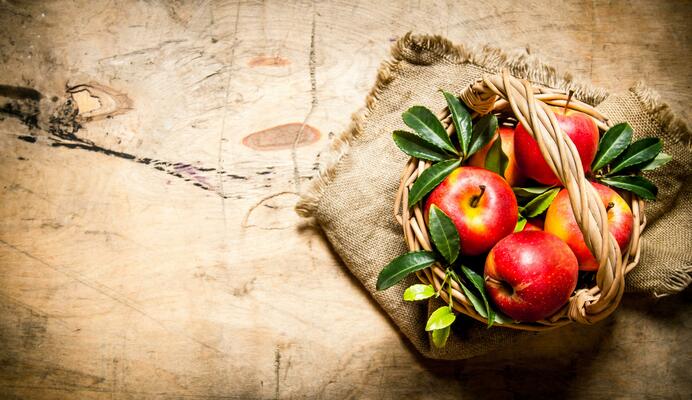 Red apples in an old basket with leaves.