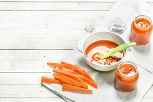 bebé alimento. bebé puré desde Fresco zanahorias con un cuchara. foto