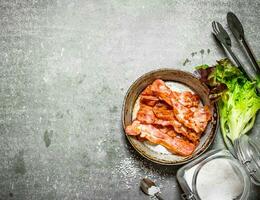 Bacon in a frying pan with salt and herbs. photo