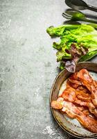Bacon in a frying pan with salt and herbs. photo