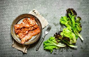 Fried bacon and greens. On stone background. photo