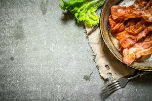 Fried bacon and greens. On stone background. photo