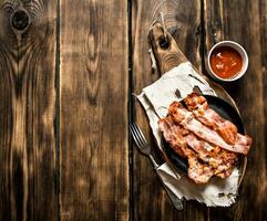 Fried bacon in a frying pan and tomato sauce. photo