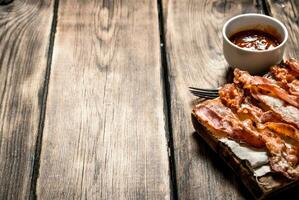 Fried bacon with tomato sauce. On wooden background. photo