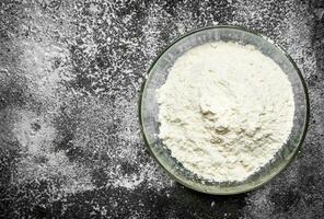 Bowl of flour on a rustic background. photo