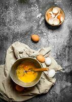 Baking background. Whisking eggs in the old bowl . photo