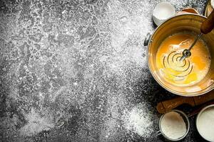 Baking background. Whisking fresh eggs in a bucket on a rustic background. photo