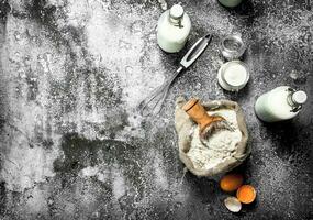 Baking background. Flour with fresh milk in bottles, sour cream and eggs. photo