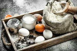 Baking background. Ingredients for dough in a wooden tray. photo