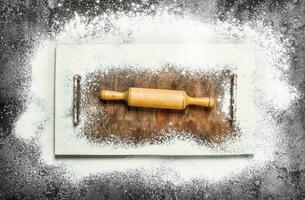 Baking background. Rolling pin for dough on the cutting board. photo