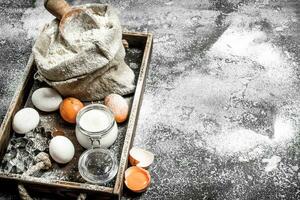 Baking background. Ingredients for dough in a wooden tray. photo