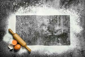 Baking background. A frame of flour with a rolling pin and fresh eggs. photo