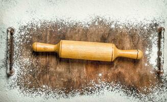 Baking background. Rolling pin for dough on the cutting board. photo