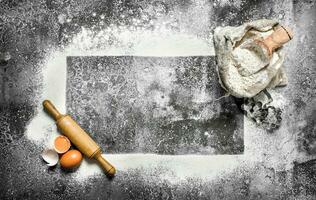 Baking background. A frame of flour with a rolling pin and fresh eggs. photo